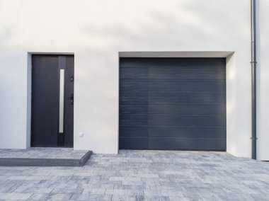 Modern House Entrance with Dark Garage Door. clipart