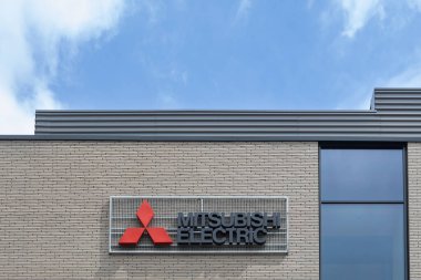 Poznan, Polonya. 09 Ağustos 2024: Açık mavi gökyüzü altındaki modern tuğla bir binanın üzerinde Mitsubishi Electric logosu.