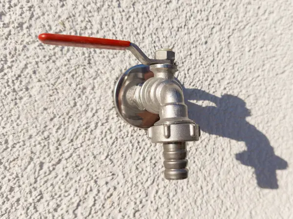 stock image Silver Outdoor Faucet with Red Handle on Textured Wall