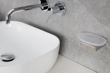 Boş sabun tabağı ve krom musluğu olan minimalist banyo.