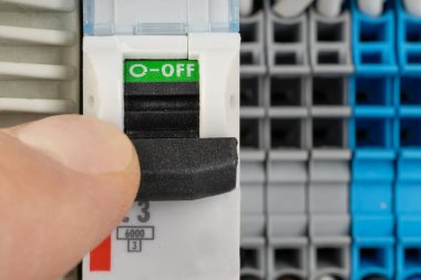 Hand switching off electrical circuit breaker in panel clipart