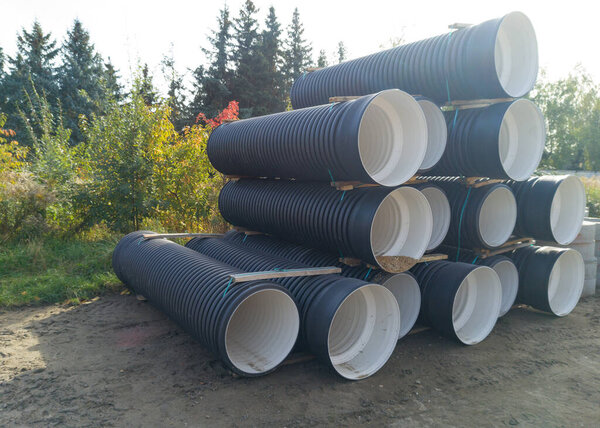Stacked corrugated drainage pipes at construction site
