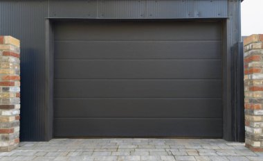 Modern black garage door with brick pillars clipart