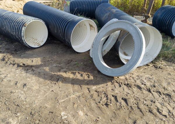 Loose drainage pipes and concrete rings on construction site