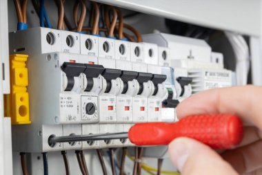 Electrician Testing Circuit Breaker with Red Handle Screwdriver clipart