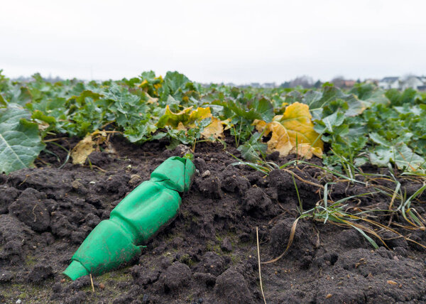 Crushed Green Plastic Bottle Polluting Agricultural Soil