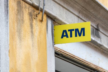 Venedik, İtalya - 19 Nisan 2025: Venedik Caddesi 'ndeki yıpranmış bina cephesinde sarı ATM işareti