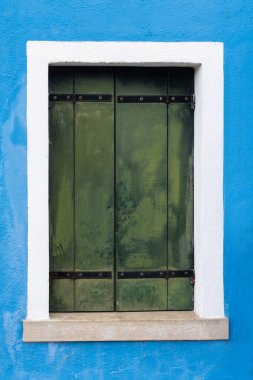 Burano 'daki mavi duvarda eski yeşil panjur.