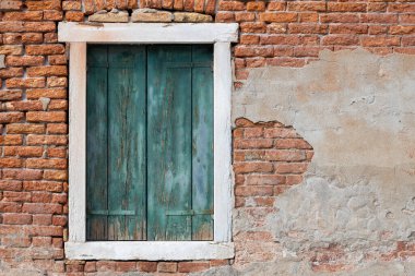 Kırsal tuğla duvarda alçı soyan yaşlı yeşil pencere panjurları