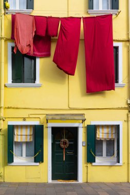 Burano İtalya 'da asılı kırmızı çamaşırlı sarı ev