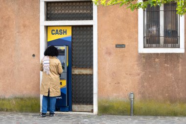 Murano, İtalya - 18 Nisan 2025: Murano Adası 'ndaki Euronet ATM' den para çeken kadın