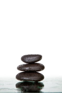 Islak siyah spa taşları izole edilmiş.
