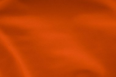 Yumuşak katlanmış parlak turuncu kumaş tekstil dokusuna yakın çekim