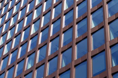 Kahverengi şebeke ve cam pencereli modern ofis binası cephesi