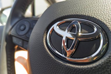 2025 yazında Leszno 'da yakalanan modern arabanın içindeki dokulu direksiyon simidi üzerindeki Toyota logosunu kapat..