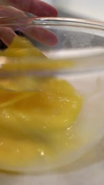 Dişi eller çırpıcıyla bir kasede yumurta çırpıyor. dikey görüntüler