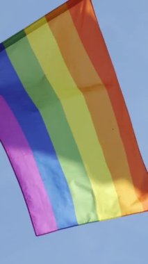 Barcelona 'nın Sitges şehrinde rüzgarda uçuşan gay gururlu gökkuşağı bayrağı. Dikey görüntüler