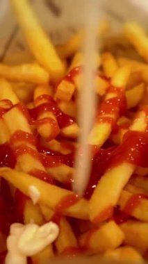 Patates kızartmasının üzerine ketçaplı mayonez sosu döküyorum. Popüler fast food, bol kızarmış patates cipsi. Dikey video