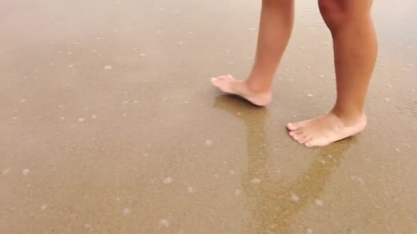 这是一个慢镜头 记录了一个孩子的脚在海滩上奔跑 被海浪浸透的情景 — 图库视频影像