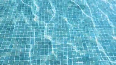 Saf mavi şeffaf su ve havuzda güneşten gelen ışık demetleri. Yaz, lüks, spa ve tatil köyü kavramları