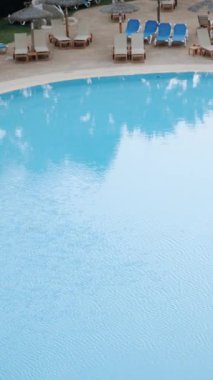 Bu büyüleyici videoyla lüks bir dünyaya adım atın. Lüks bir otelde tropikal ya da Akdeniz tarzı bir havuzun geniş bir görüntüsünü sergileyin. Sahne büyüleyici saman şemsiyelerle süslenmiş.