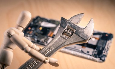 Arka planda ingiliz anahtarı ve sökülmüş telefonu olan ahşap bir kukla. Onarım ve Avrupa komisyon önerisi olarak kavramlara uygundur