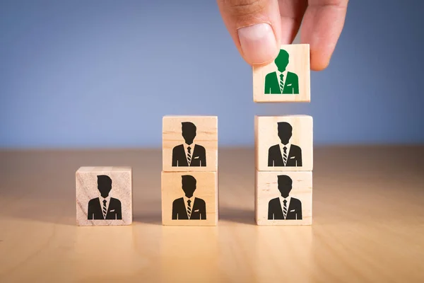Hand grabbing green leader businessman icon wooden block. Business job hiring recruitment selection. Career opportunity human resource management human resource management leadership employees team
