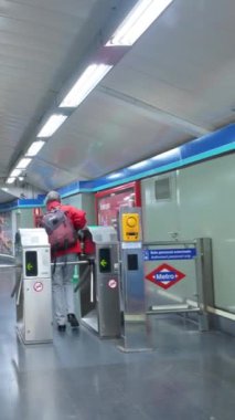 Madrid, İspanya. 6 Kasım 2023: Madrid, İspanya 'da metro istasyonundaki toplu taşıma aracıyla bir metro istasyonuna giren ve turnikelerden geçen yolcu