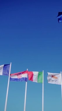 Mavi gökyüzüne karşı İrlanda, İspanya, Yunanistan, Fance ve Hırvatistan 'ın bayrakları. Yavaş çekim ve dikey görüntüler