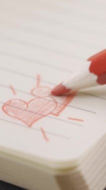 Elle aşk kalplerini kırmızı kalemle ahşap bir masanın üzerine çizmek. Aşk, sevgililer günü, yıldönümü, çift ve arkadaşlık kavramları için uygun..