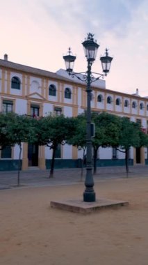 İspanya, Seville 'deki Patio de Banderas avlusunun manzarası. Turuncu ağaçlarla çevrili geniş bir meydan, tarihi binalarla çevrili, Giralda kulesinin manzarasını sunuyor, Real Alcazar de Sevilla 'nın yanında..