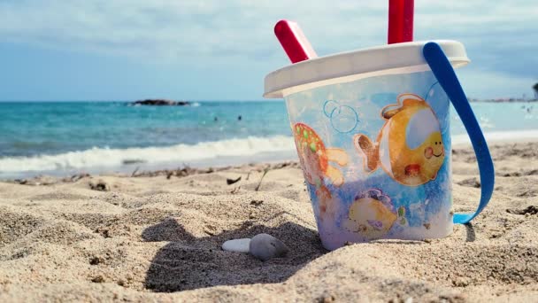 为孩子们准备的海滩水桶 装有红色铁锹和带有异想天开的鱼和泡泡图案的水桶 这套水桶非常适合享受夏日的阳光 沙滩和大海 这是一个伟大的玩具 — 图库视频影像