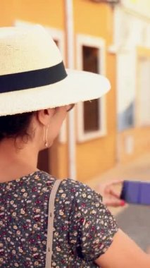 , Alicante Eyaleti, İspanya Denia dar ve pitoresk cadde bir resim alarak saman güneş şapkası ile mutlu turist kadın. , Alicante, Ispanya. Deniz mavisi ve portakal stili.