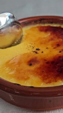 Kaşık Katalan kremine battı, yakın çekim. Yumurta ve sütten yapılan katalan kreması, Fransız creme brulee 'sine benzer ama İspanya' nın tipik Katalonya bölgesidir. Dikey video