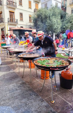 Valencia, İspanya, Mart 2024: Valencia 'daki Fallas şenlikleri sırasında sokakta toplu paellalar pişiren bir grup insan.