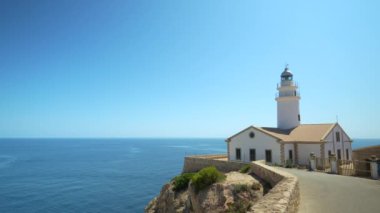 Capdepera Deniz Feneri, Mallorca 'daki engin ve sakin Akdeniz manzaralı engebeli bir uçuruma tünemişti. Berrak mavi gökyüzü ve sakin sular dingin ve büyüleyici bir manzara yaratır.