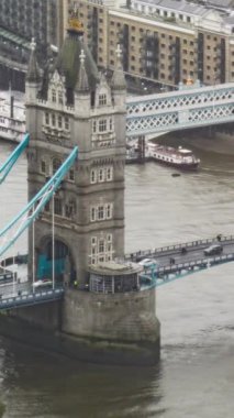 Londra 'da Thames Nehri' ni kaplayan Tower Bridge 'in yüksek açılı görüntüsü, araçların geçişi ve sudaki teknelerle.