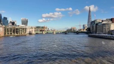 Thames Nehri 'nin geniş görünümü, açık mavi gökyüzünün altında Çömlek ve ikonik mimari de dahil olmak üzere Londra modern silüeti ile birlikte..