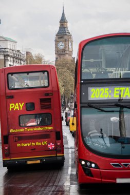 UKs 'ın yeni Elektronik Seyahat Yetkilendirmesi ya da ETA gereksinimi hakkında 2025 yılından itibaren arka planda Big Ben' le birlikte iki sembolik kırmızı Londra otobüsü tabelaları. Dijital bileşik