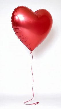 Parlak kırmızı kalp şeklinde bir balon, kurdeleli, düz beyaz bir arkaplanda yüzen, aşkı ve kutlamayı simgeleyen.