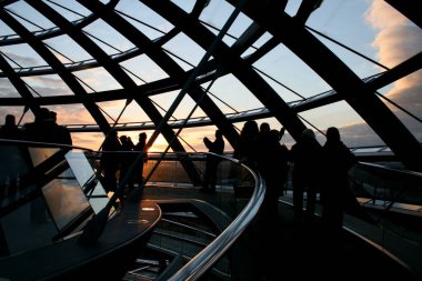 Berlin, Almanya 'daki Reichstag Kubbesi' nden günbatımının keyfini çıkaran isimsiz ve tanınmayan turistlerin siluetleri.