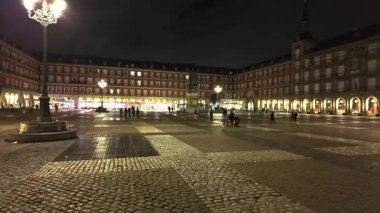 Turistler ve yerliler geceleyin Madrid 'deki Plaza Mayor' un canlı atmosferinin tadını çıkarıyorlar.