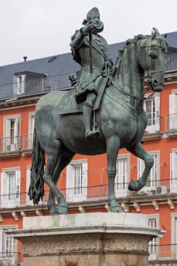 İspanya, Madrid 'deki Plaza Belediye Başkanı at sırtında Kral III. Philip' in bronz binicilik heykeli tarihi binalar ve bulutlu gökyüzü