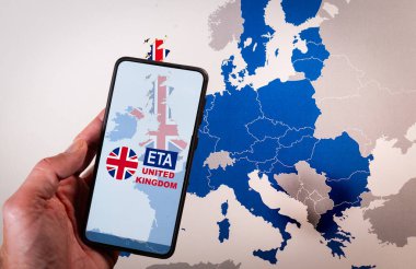 Arkaplanda Avrupa haritası bulunan akıllı telefon ekranında Birleşik Krallık 'a ETA veya Elektronik Seyahat Yetkilendirmesi