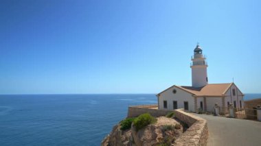 Kayalık kayalıklara bakan beyaz capdepera deniz feneri. Sakin mavi deniz manzarası sunuyor. Mallorca 'da nefes kesici manzara.