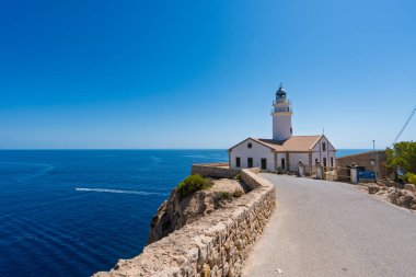 Kayalık kayalıklara bakan beyaz capdepera deniz feneri. Sakin mavi deniz manzarası sunuyor. Mallorca 'da nefes kesici manzara.