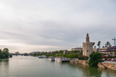 Torre del Oro, Guadalquivir Nehri 'ni gün batımında, Seville, Endülüs ve İspanya' da rıhtımlı teknelerle yansıtıyor.