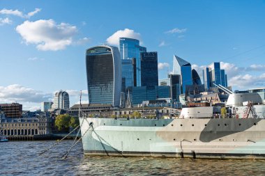 Hms Belfast, kasaba sınıfı bir hafif kruvazör, Thames nehrinde gururla oturur, modern Londra siluetine karşı yan yana dizilmiştir.