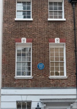 Beyaz pencereli tuğla duvar ve beatles 'ın Londra' daki 3 Savile Row 'daki çatı konseri anısına mavi plaket.