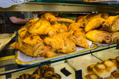 Lezzetli altın kruvasanlar ve diğer hamur işleri Paris 'teki bir pastanede sergileniyor, eğlenmeye hazır.